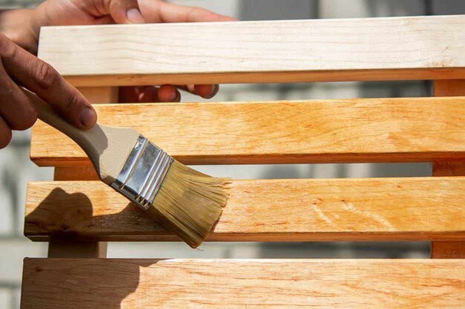 Person painting wooden surface